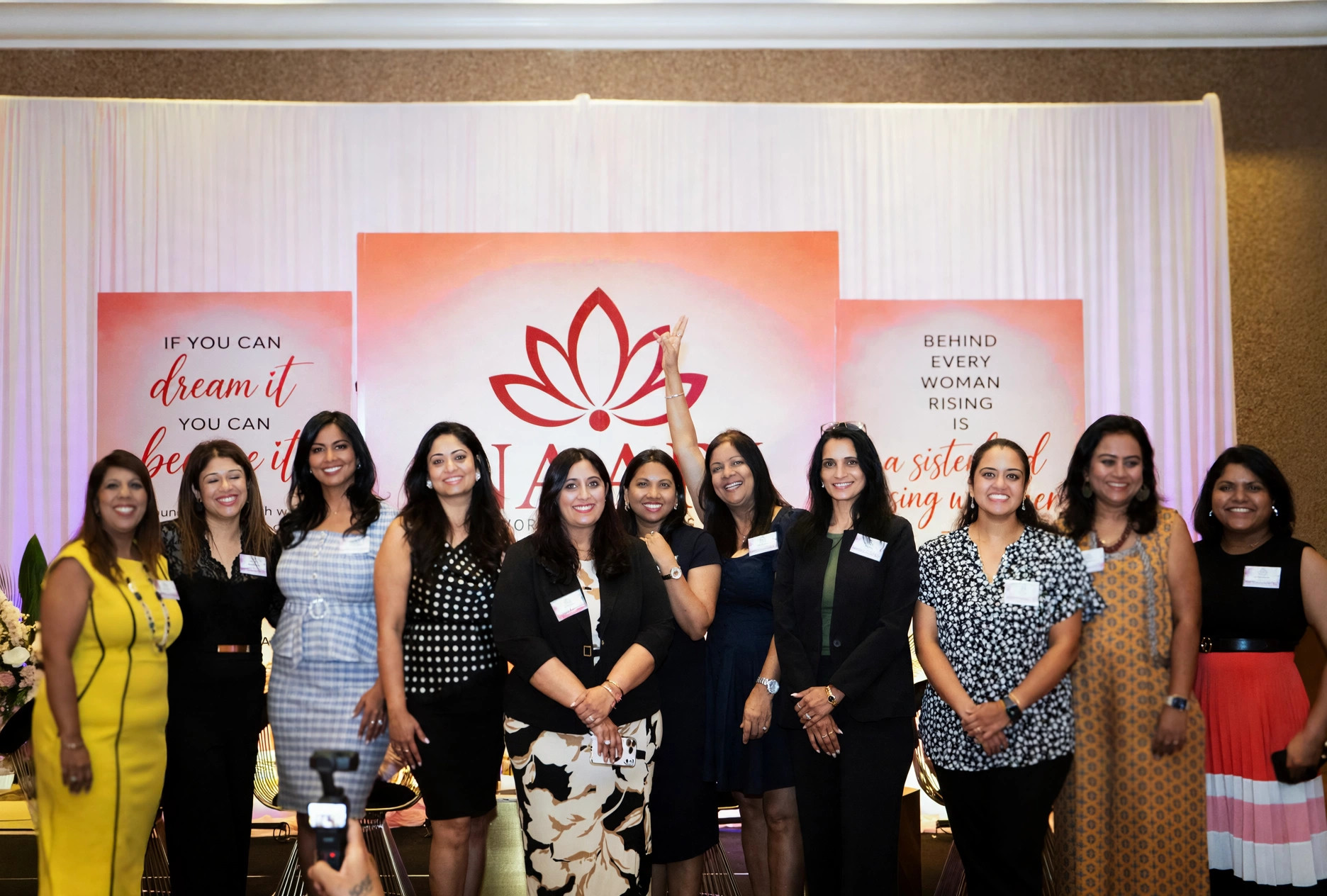 Ten women celebrating together at the NAARI backdrop
