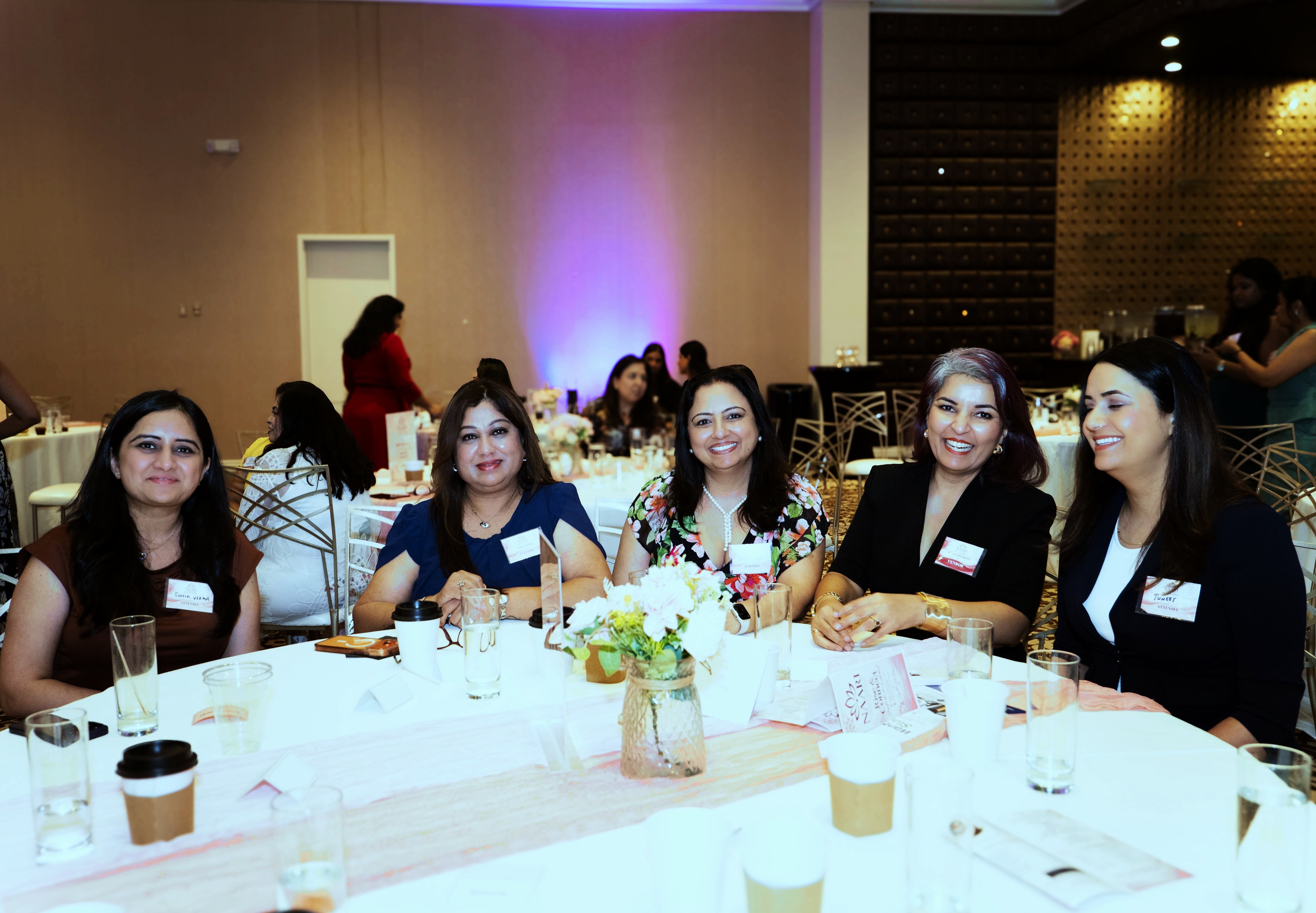 Six women laughing together at a round table